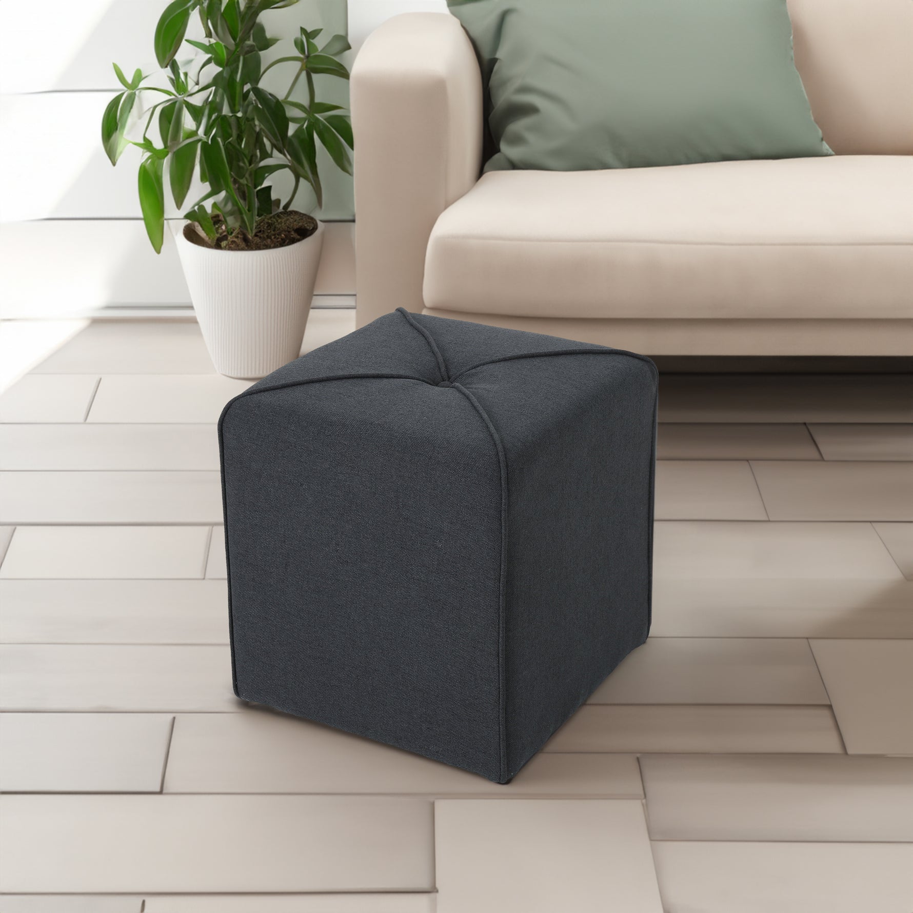 Pouf ottoman eprolo en tissu gris avec couture élégante, utilisé comme siège ou repose-pieds dans un salon contemporain