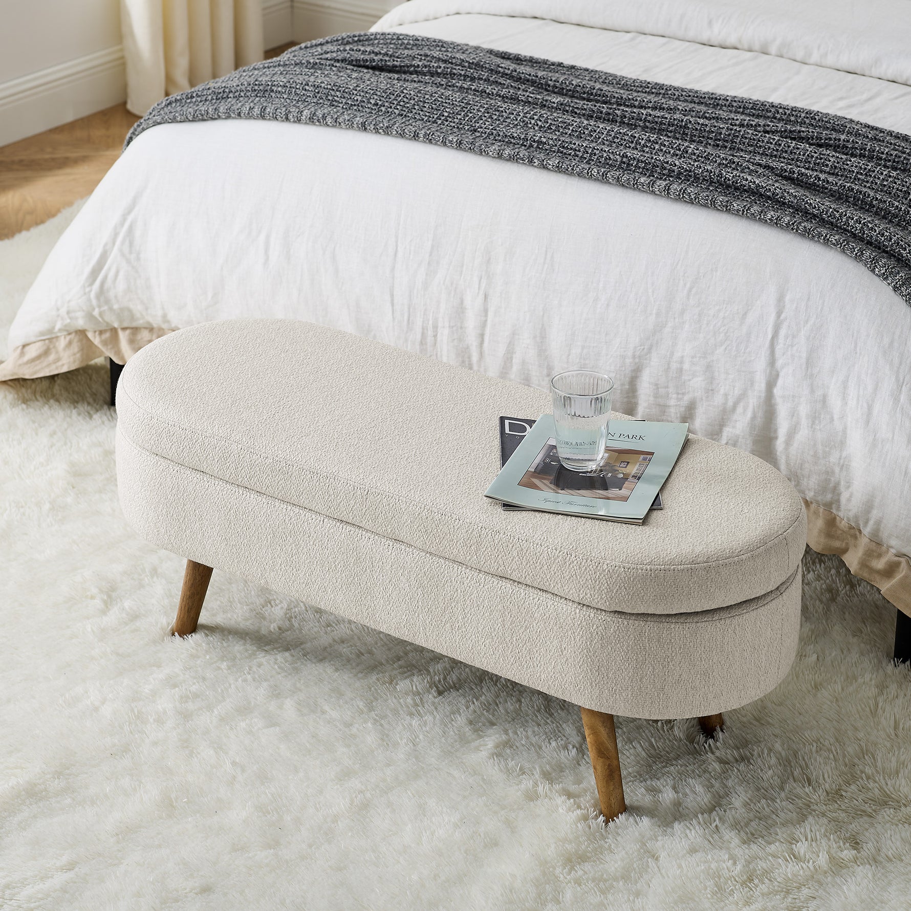 Banquette coffre ovale beige avec pieds en bois de caoutchouc, dimensions 43,5"x16"x16", meuble de rangement élégant et pratique.